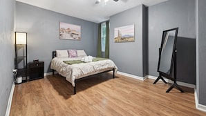 A bedroom with a bed, a ceiling fan, a standing mirror, and two framed pictures on the wall. - 2BR 1Bath 4 Beds Entire Apartment in Bloomfield (Pittsburgh)