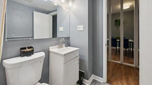 A bathroom with a toilet, sink, and mirror. - 2BR 1Bath 4 Beds Entire Apartment in Bloomfield (Pittsburgh)