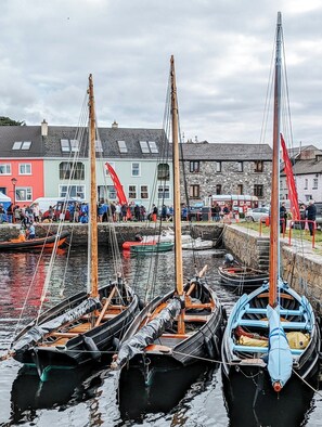 En havn med fortøjede både, mange mennesker og bygninger i baggrunden.