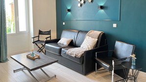Uma sala de estar moderna com um sofá, duas poltronas, uma mesa de centro e um lustre fixado na parede.