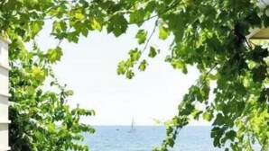 A view through a doorway with a clear sky and a distant sailboat on the water.