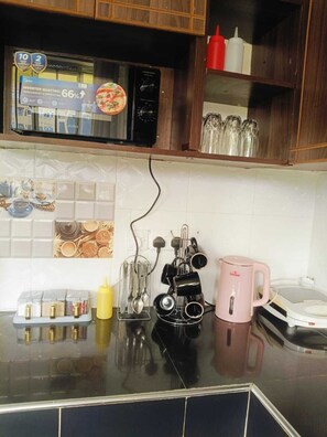 Une cuisine équipée d’un four à micro-ondes, d’une bouilloire, d’une machine à café et d’un porte-ustensiles.