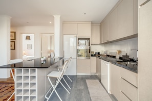 A modern kitchen with a central island, white cabinetry, and a built-in microwave. - Santar M Terrace by Homing (Santarém)