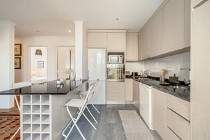 Una cocina moderna con una isla central, armarios blancos y un microondas integrado.