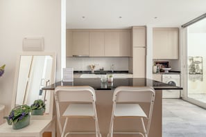 A modern kitchen with a central island, white chairs, and a view through a large window. - Santar M Terrace by Homing (Santarém)