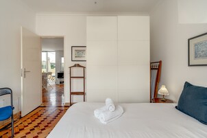 Una habitación de hotel con una cama, una silla, una mesa, una lámpara y un cuadro en la pared.