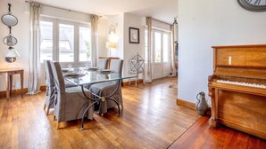 Un comedor con una mesa de vidrio, sillas y un piano.