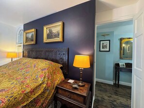 A room with a bed, two framed pictures on the wall, a nightstand with a lamp, and a dresser with a mirror. - St. James Cottage (Liskeard)
