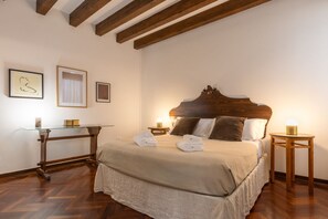Ein Schlafzimmer mit einem hölzernen Bett, einem Glastisch und einem Nachttisch aus Holz.