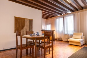 A dining area with a wooden table and chairs, a sofa, and a window with curtains. - Welcome to Squero Home, a welcoming and refined residence in the heart of Venice, just behind Piazza San Marco and facing on the famous Calle with boutiques and designer labels.Located on the second floor of a building with an elevator, this apartment co (Venice)