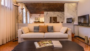 Una sala de estar moderna con un sofá, una mesa de centro con una revista, un televisor y una chimenea.