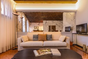Ein modernes Wohnzimmer mit einer Couch, einem Couchtisch mit einer Zeitschrift, einem Fernseher und einem Kamin.