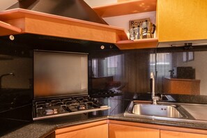 A modern kitchen with a black stove, stainless steel sink, and wooden cabinets. - Welcome to Squero Home, a welcoming and refined residence in the heart of Venice, just behind Piazza San Marco and facing on the famous Calle with boutiques and designer labels.Located on the second floor of a building with an elevator, this apartment co (Venice)