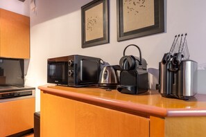 Eine Küche mit Mikrowelle, Wasserkocher und Kaffeemaschine auf der Arbeitsfläche, einem Bilderrahmen an der Wand und einem Messerblock.