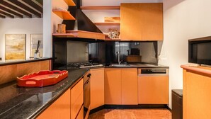 Una cocina moderna con armarios de madera, encimera negra y lavavajillas integrado.