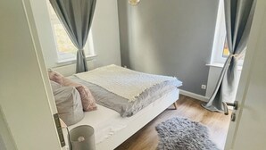 Quarto com cama, luminária, tapete fofo e luminária pendente.