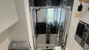 Casa de banho compacta com chuveiro, lavatório e um porta-toalhas.