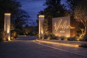 A well-lit entrance with a sign reading 'Vaha Bitez,' surrounded by trees and a curved pathway.