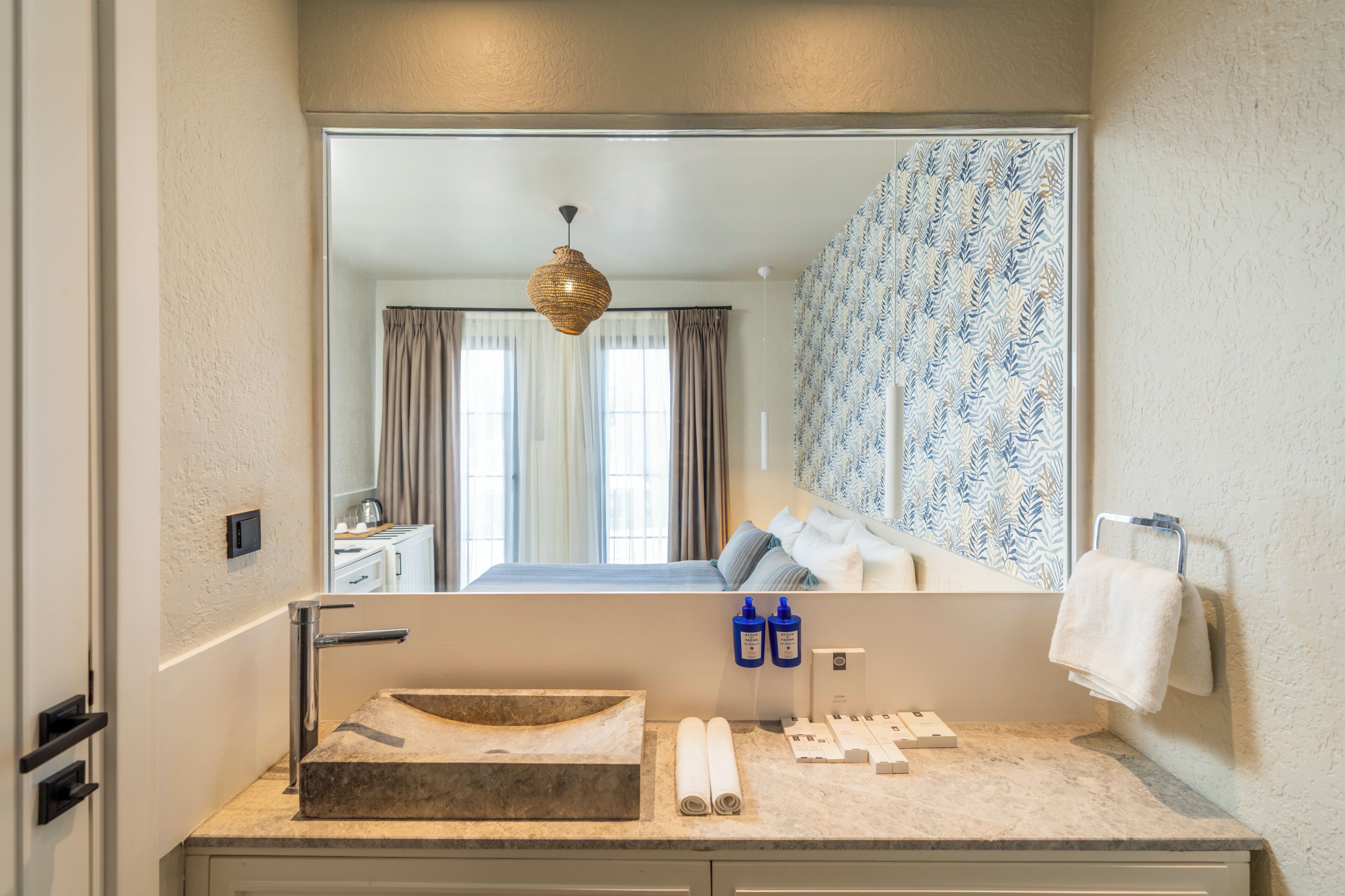 Un baño con un espejo grande, un lavabo y un perchero para toallas.