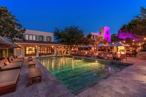 A pool area with lounge chairs and umbrellas, a building with a flat roof, and trees in the background. - Vaha Bitez Boutique Hotel (Bodrum)