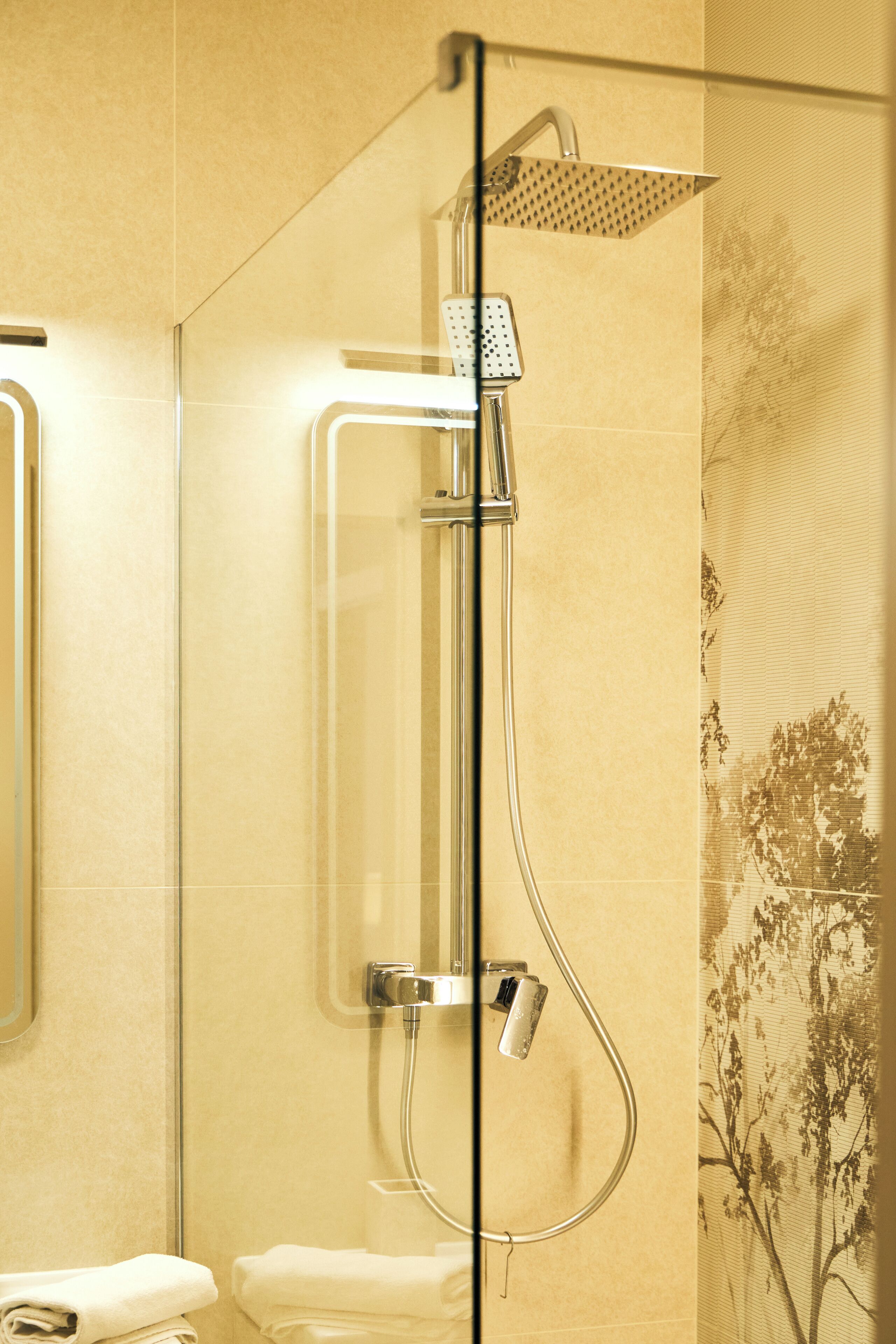 A modern bathroom with a glass-enclosed shower, a toilet, and a towel rack.