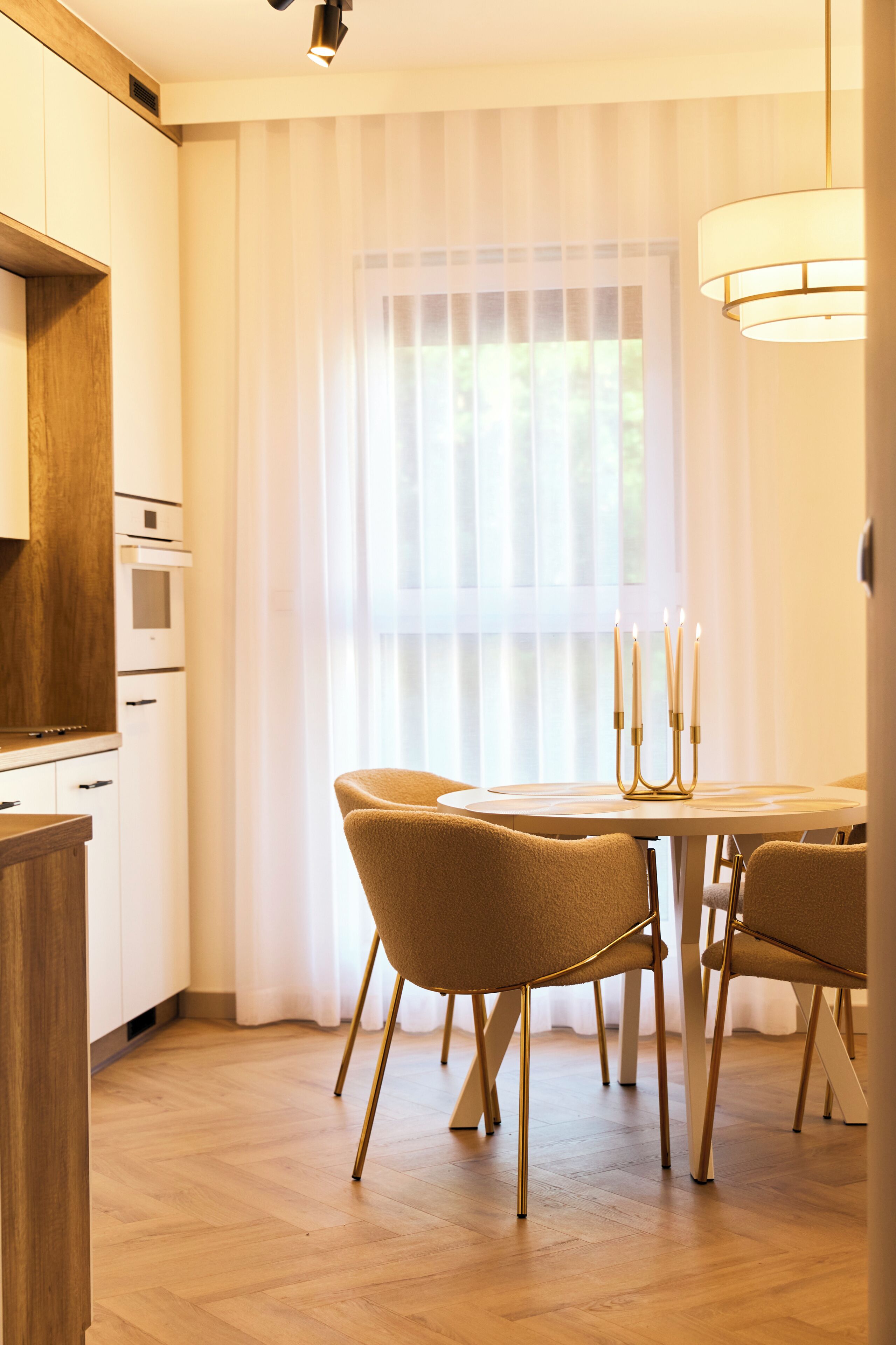 Una cocina moderna con armarios de madera, una mesa de comedor con cuatro sillas y una araña iluminada.