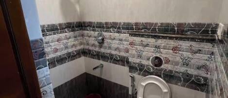 A bathroom with a toilet, sink, shower, and patterned tiles.