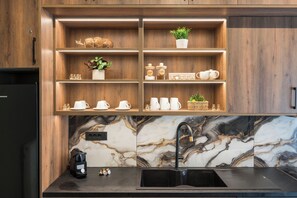 Eine Küche mit Holzschränken, Marmorfliesenspiegel und einem schwarzen Spülbecken.