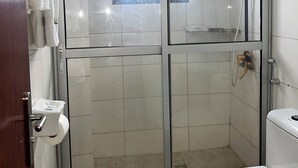 A bathroom with a glass-enclosed shower, a toilet, and a towel rack.