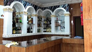 A bar area with a marble ceiling, wooden paneling, and a variety of liquor bottles.