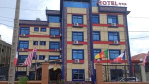 A multi-story hotel with a prominent 'HOTEL' sign, multiple flags, and a gated entrance.