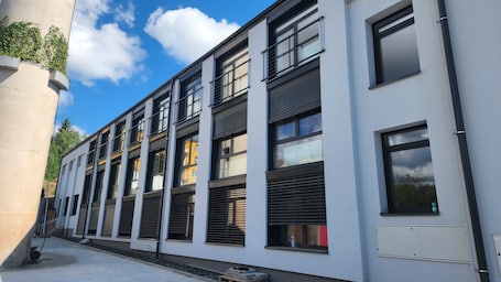 A modern building with multiple windows and a white facade.. Microbyty & Apartments