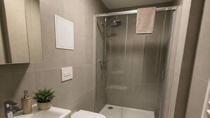 A modern bathroom with a shower, toilet, sink, and cabinet. - Microbyty & Apartments  (Ústecký kraj)