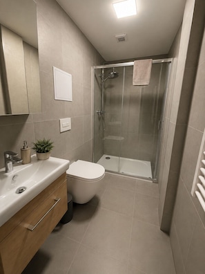 Ein modernes Badezimmer mit Dusche, Toilette, Waschbecken und Schrank.