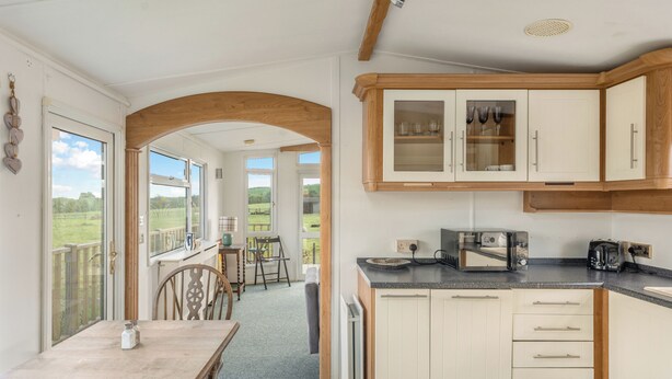A kitchen with wooden cabinets, a dining area with a table and chairs, and a view of the outdoors.
