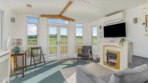A living room with a fireplace, a television, and a view of the outdoors.