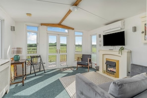 Una sala de estar con chimenea, televisión y vistas al exterior.