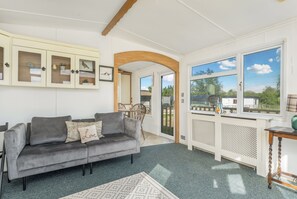 Una sala de estar con un sofá gris, un arco de madera, un armario blanco con puertas de vidrio y vistas amplias a través de grandes ventanales.