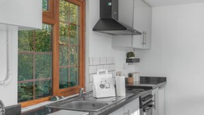 Cozinha moderna com uma janela grande, eletrodomésticos de aço inoxidável e armários brancos.