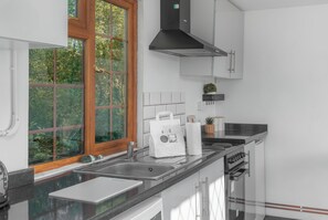 Una cocina moderna con un ventanal grande, electrodomésticos de acero inoxidable y armarios blancos.