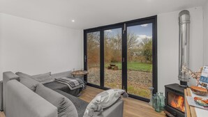 Un salon moderne comprenant un canapé, une table, une cheminée et une porte-fenêtre coulissante donnant sur un jardin.