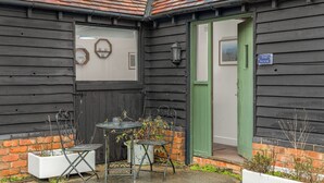 A small outdoor seating area with metal chairs and a table, a green door, and a sign reading 'The Nook'. - The Nook - Cosy Rural Cottage with Stunning Views (Charndon)
