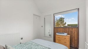 A bedroom with a bed, a dresser, a radiator, a window, and a door. - The Nook - Cosy Rural Cottage with Stunning Views (Charndon)