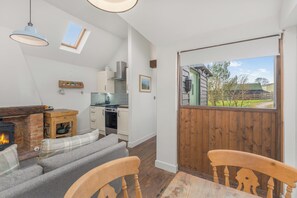 Ein gemütliches Wohnzimmer mit Kamin, einem Esstisch und einer Küche im Hintergrund.