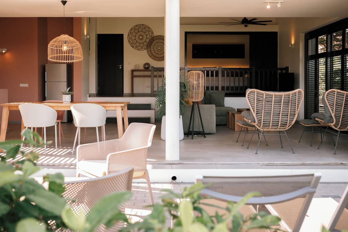 A modern outdoor dining area with wicker chairs, a wooden table, and hanging wicker lamps.