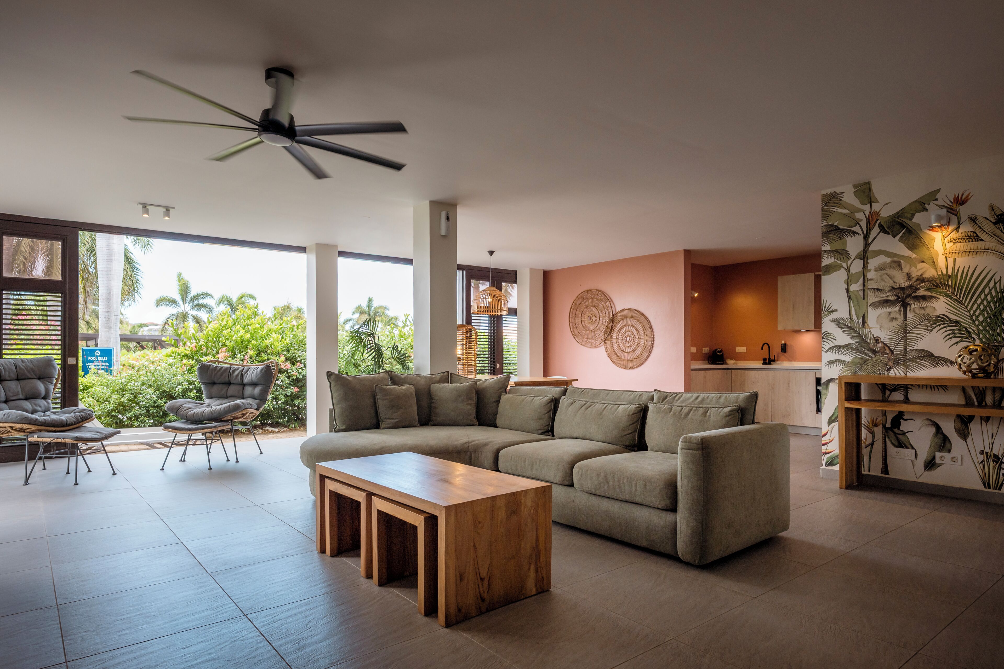 A modern living room with a sofa, chairs, a wooden coffee table, and a ceiling fan.