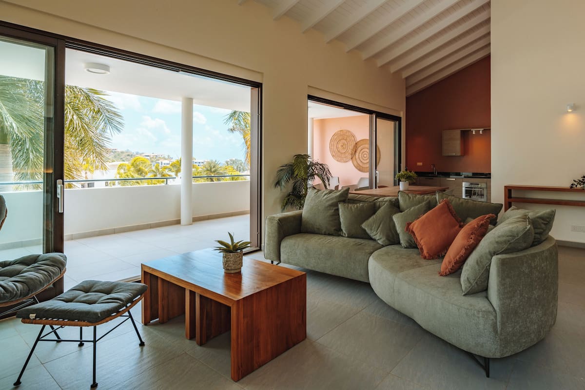 A modern living room with a sofa, coffee table, and a view of the outdoors.