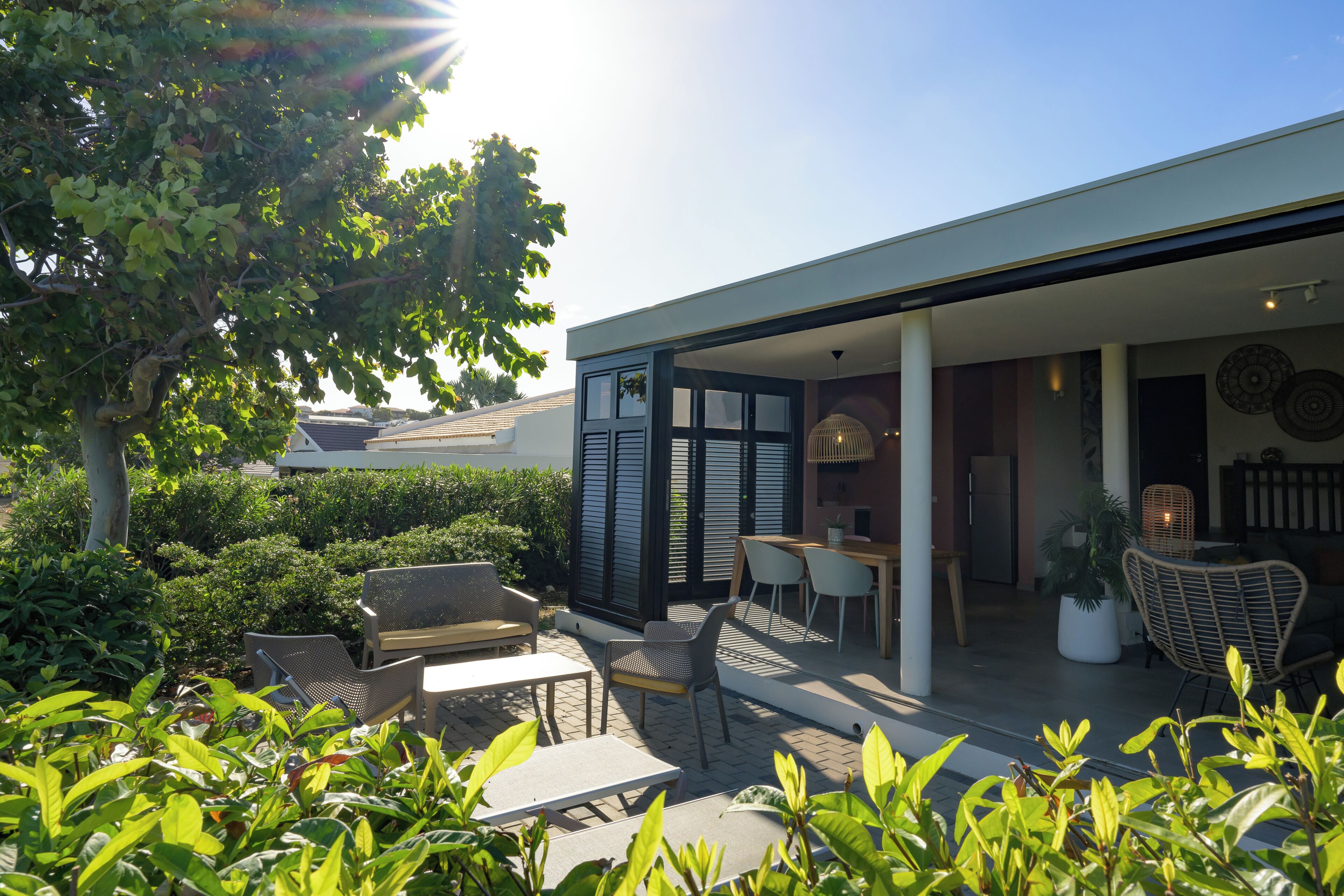 A modern outdoor patio with seating, a dining area, and a view of the surrounding greenery.