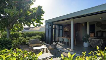 A modern outdoor patio with seating, a dining area, and a view of the surrounding greenery.