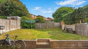 A backyard with a brick wall, a wooden fence, a bicycle, and a wooden bench. - Badger Haven, Apt 3 1st floor self contained apartment in Brackley (Brackley)
